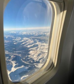 View from inside the airplane looking out window at the mountains
