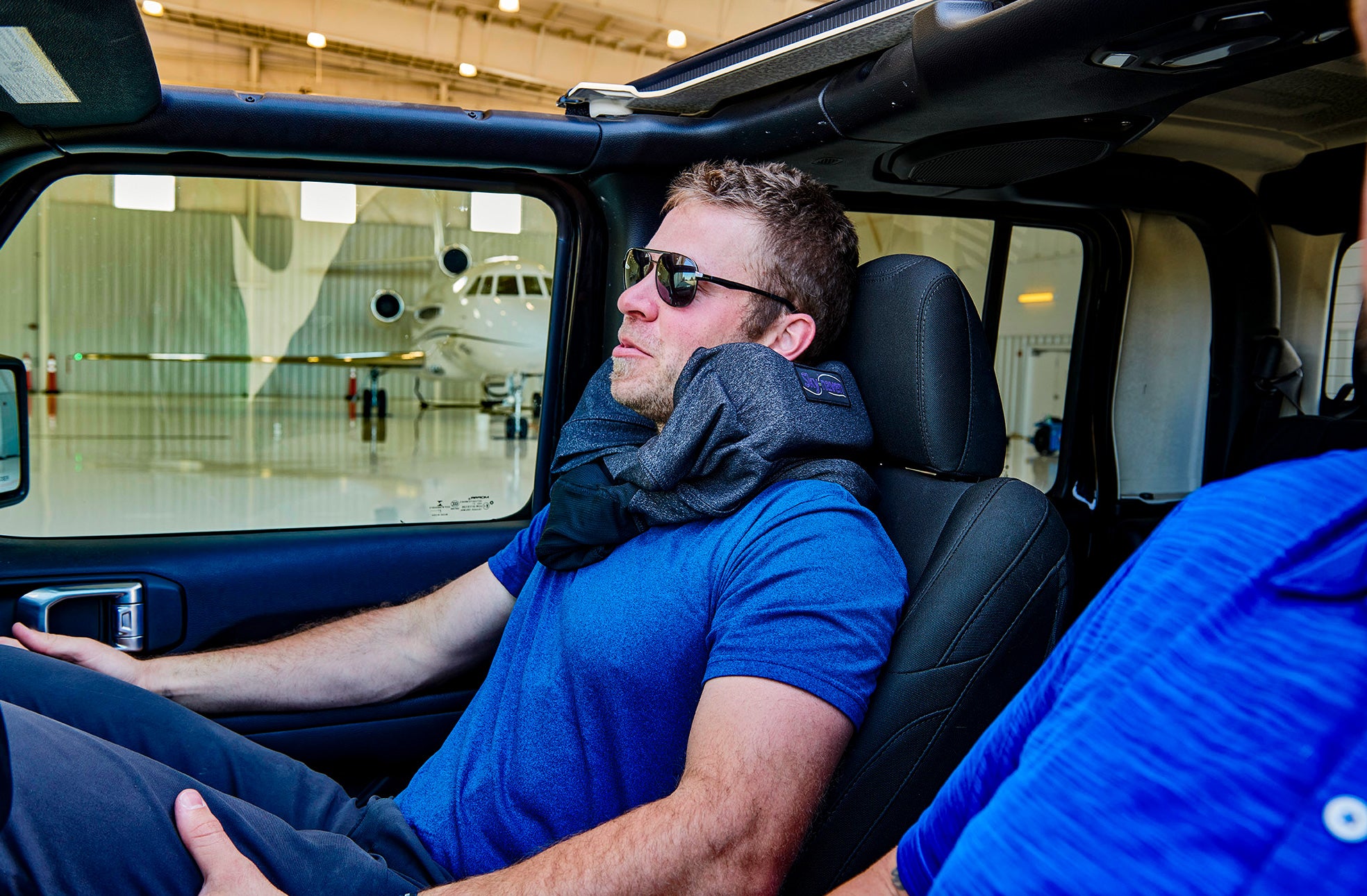 young male wearing his gray sleep hoodie at an airplane hanger