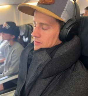 charcoal gray sloodie being worn on plane with headphones and hat on