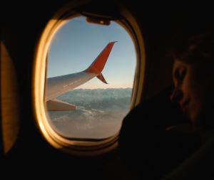 window plane seat sleeping looking out window and seeing red plane wing